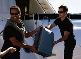 Men loading suit cases onto a yacht