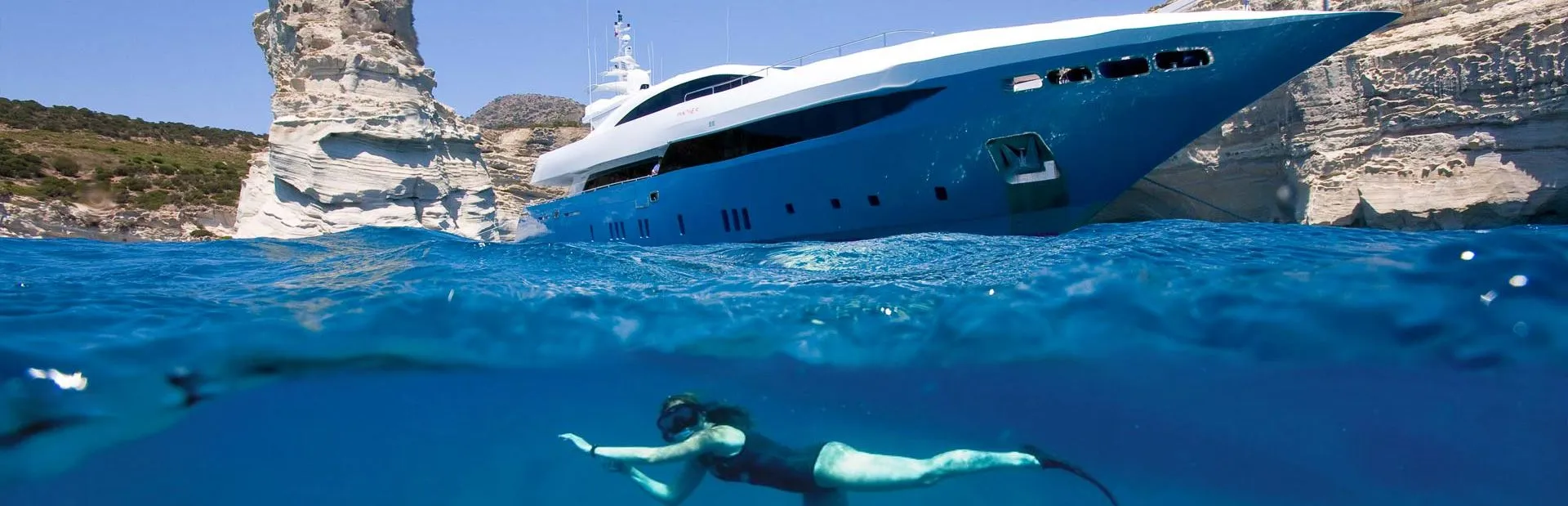 person underwater snorkeling and superyacht